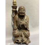 A Chinese root carved figure of Buddha raised on a pierced integral stand, converted to an