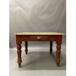 A late 19th century pine kitchen table with small drawer to apron on turned legs stained in fox red,