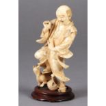 A Japanese ivory okimono of a man, startled and frightened by a dog as it bares its teeth at him,