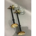 A pair of Edwardian wall lights on long ebonised straight arms with knop finials and clear glass