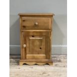 A pine bedside cabinet having a drawer over a single door cupboard