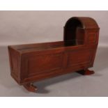 A 19TH CENTURY MAHOGANY CRADLE, having an arched and reeded hood with hinges, bead-panelled sides
