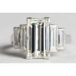 A DIAMOND BAGUETTE CUT RING IN PLATINUM circa 1960, the principle stone flanked by four smaller