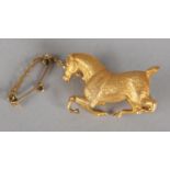 A HORSE BROOCH, cast and engraved in full relief with docked tail, in yellow metal (tests as 14ct