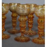 A 19TH CENTURY SET OF TWELVE GERMAN AMBER HOCK GLASSES, the cup-shaped bowls etched with hunting