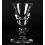 A MID 18TH CENTURY TAVERN GLASS with thick bottomed rounded funnel bowl, above a bulbous knop with