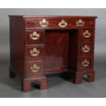 A GEORGE II MAHOGANY AND CROSSBANDED KNEEHOLE DESK, having a moulded rim, the drawer across fitted