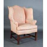 A GEORGE III STYLE MAHOGANY WINGED ARMCHAIR having an arched back and deep serpentine wings and seat