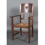 AN ARTS AND CRAFTS OAK OPEN ARMCHAIR by W J Neatby, the broad panel carved with an inverted heart-