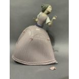 A Lladro figure of a young girl in a full skirted gown holding a masquerade mask, 27cm high, (handle