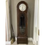 An early 20th century mahogany and glazed longcase clock of arched profile having a silvered dial