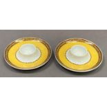 A pair of Rosenthal porcelain egg cups for Versace, yellow glaze with formal border in shades of