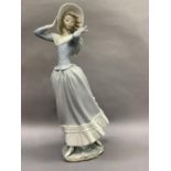 A Lladro figure of a young woman holding her hat against the wind, signed to the base and dated 19.