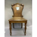 A Victorian oak hall chair having a painted shield to the back on turned legs