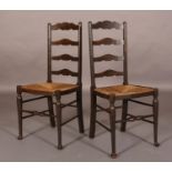 A PAIR OF 19TH CENTURY OAK LADDER BACK AND RUSH SEATED SINGLE CHAIRS on slender rounded and