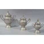 A graduated set of three Eastern lidded two handled urns, embossed overall with stylised flower
