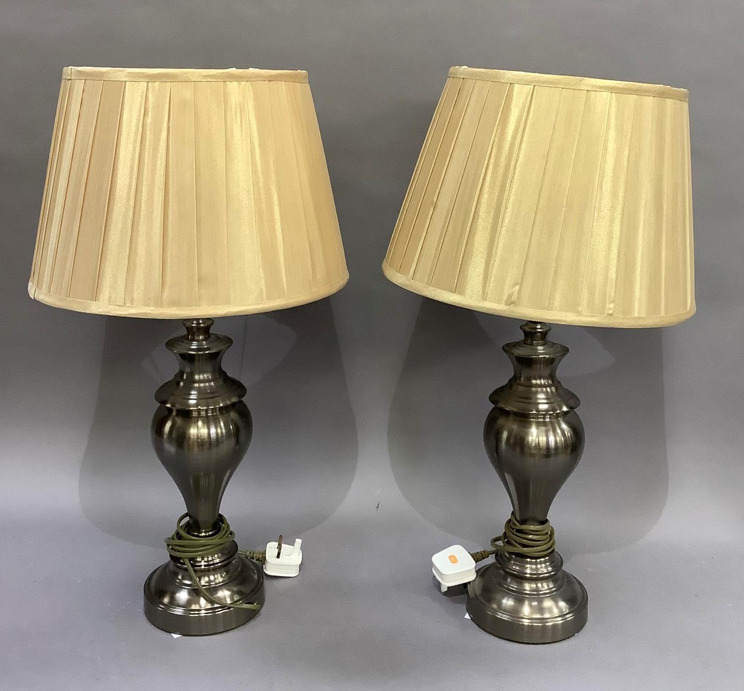 A pair of pewter coloured table lamps of baluster form on circular bases complete with shades,