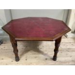 An octagonal library table with red leather incised surface on turned legs