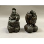 A pair Chinese of bronze effect figures depicting a man with a large sack upon his back standing