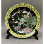 A Chinese plaque enamelled with peacocks amongst peonies on a black ground with yellow border, 37cm