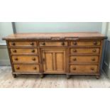 A Victorian oak dresser base having three drawers across, recessed cupboard with twin indented panel