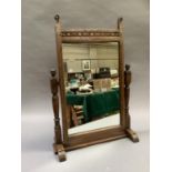 An oak framed toilet mirror of rectangular outline with gouge cut decoration to the frame, on turned