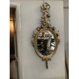 A gilt wood oval wall mirror with a ribbon tied rose garland cresting, the frame moulded with riband