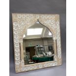 A cream washed wood wall mirror, the inner frame of arched outline within a rectangular carved frame