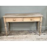 A pine kitchen side table having two drawers to the apron and on turned legs, 137cm wide x 52cm deep