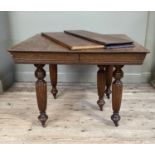 A late Victorian oak extending dining table with extra leaf on turned and reeded legs with