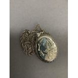 An oval silver locket and chain, foliate engraved within a twisted wire surround hung on a Prince of