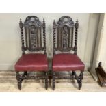 A pair of Victorian carved Jacobean style hall chairs with pierced leaf cresting and splat with rail