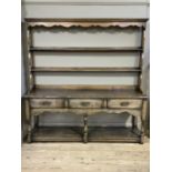 A reproduction oak dresser having an open rack with moulded cornice and shaped frieze over two