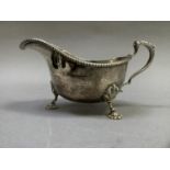 An Edward VII silver sauceboat with notched rim, leaf capped handle and on shell feet, Birmingham