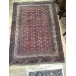 A Bokhara rug of crimson ground with four rows of elephant feet medallions within multiple