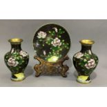 A pair of cloisonné vases and plate enamelled with rocks issuing peony against a black ground,