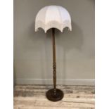 A stained beech standard lamp with turned column, circular base and tasselled shade