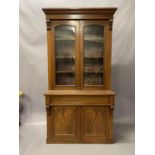 A Victorian walnut bookcase-cupboard having a moulded cornice above two glazed doors, frieze