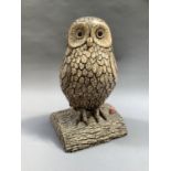 A cast concrete figure of an owl perched upon a tree trunk, finished in shades of brown, 46cm