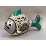 A Mexican pottery fish painted with exotic birds and foliage on a grey ground with sea green tail