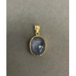 A star sapphire pendant, the oval cabochon stone collet set from a fluted pendant loop all in yellow