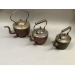 Two copper kettles of circular outline, 32cm over handle and 28cm over handle together with