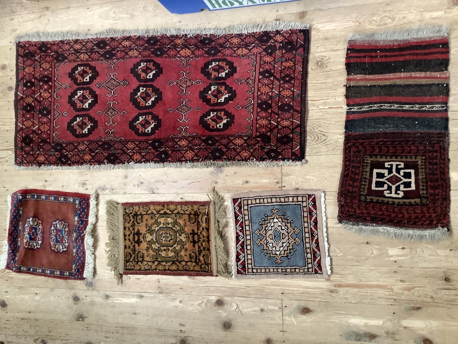 A small Bokhara rug of maroon ground of 109cm x 48cm approx, together with four small rug panels