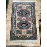 A small Middle Eastern style rug the mushroom ground having two green, mauve and navy blue octagonal