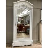 A French armoire of arched profile, pale grey finish, with mirrored door and drawer below on leaf