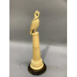 A 19th century ivory figure of a bird with snake in its beak, perched upon a wrythen column on