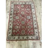 A wool carpet of coral ground and ivory border in the Persian style, 160cm x 105cm wide approx