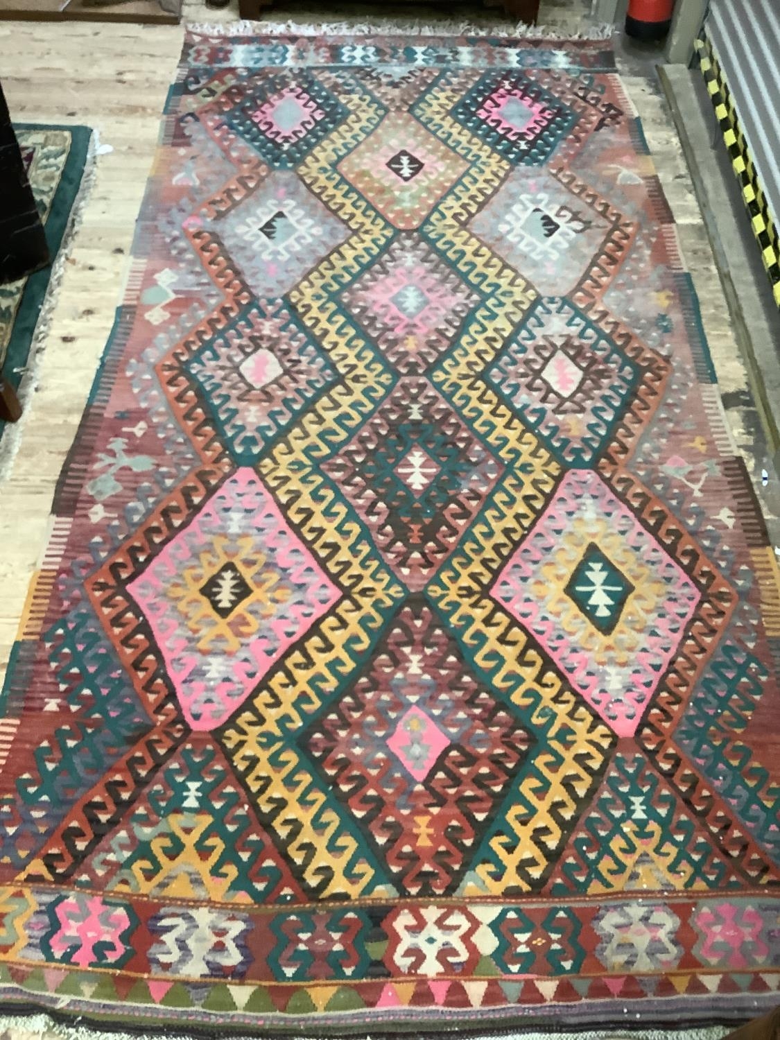 A large kelim rug of three rows of hooked diamond medallions in shades of pink, yellow, green, fox - Image 2 of 3