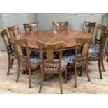 A walnut and yew wood cross banded circular dining table on four turned columns with platform and