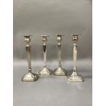 A set of four silver plated candlesticks of square tapered outline on square canted base, 23cm high